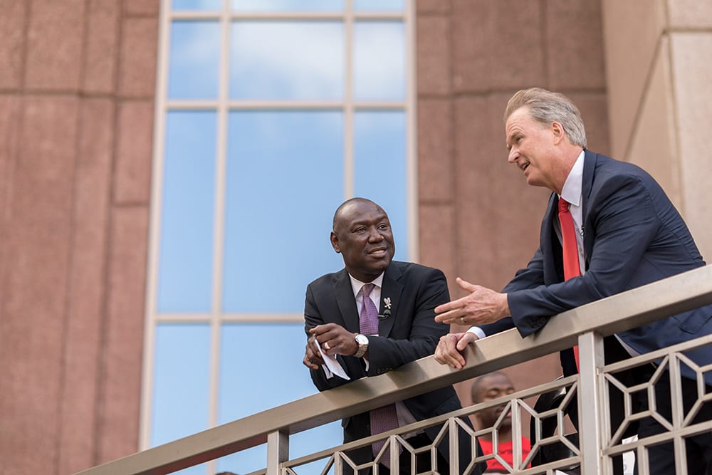 Attorneys Bob Hilliard and Ben Crump, leaning over a balcony, chatting.