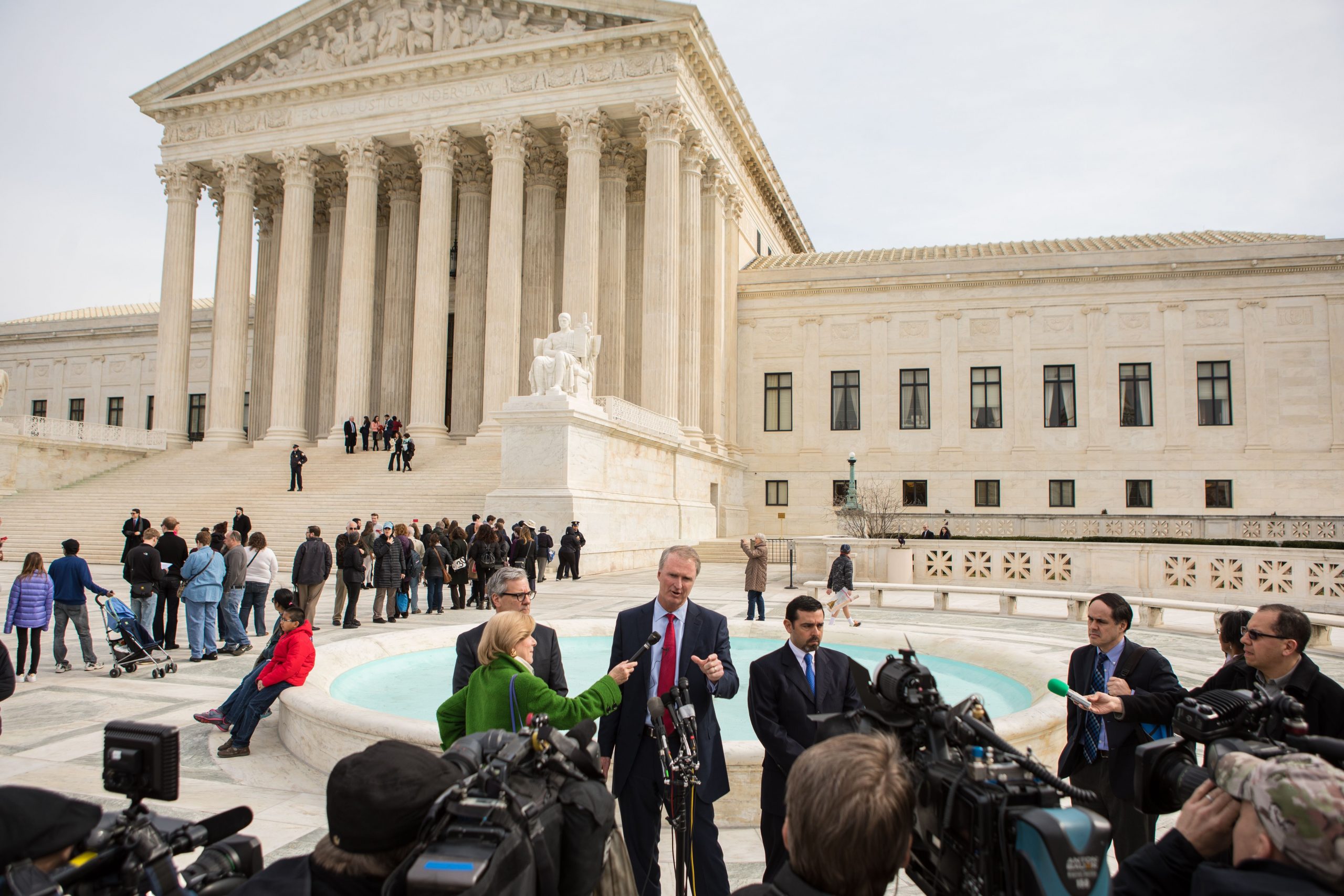 Group of journalists standing in front of the United States Supreme Court Building. Attorney Bob Hilliard is answering questions.