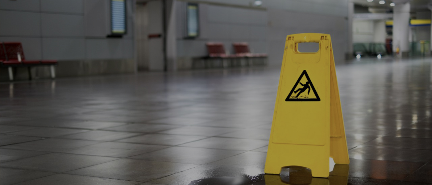 image of an empty space, in the foreground is a yellow caution sign alluding to a wet floor, warning against a slip and fall