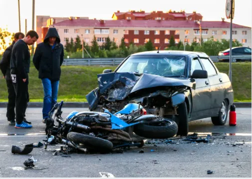 Two people looking at the accident between a car and motorcycle.