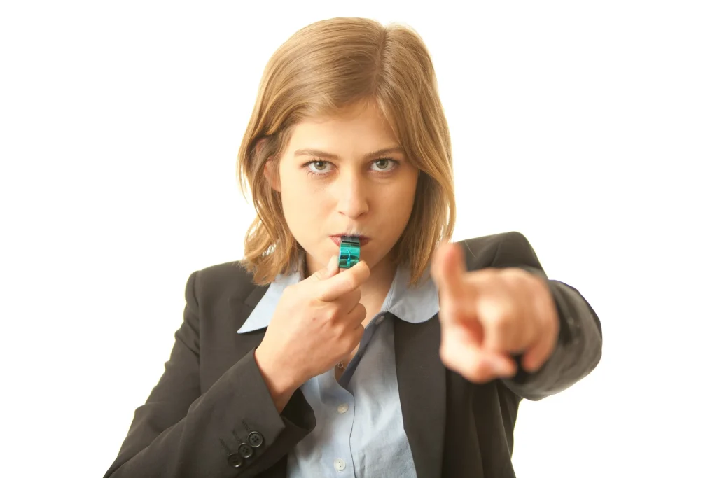 An employee blowing a whistle and pointing.