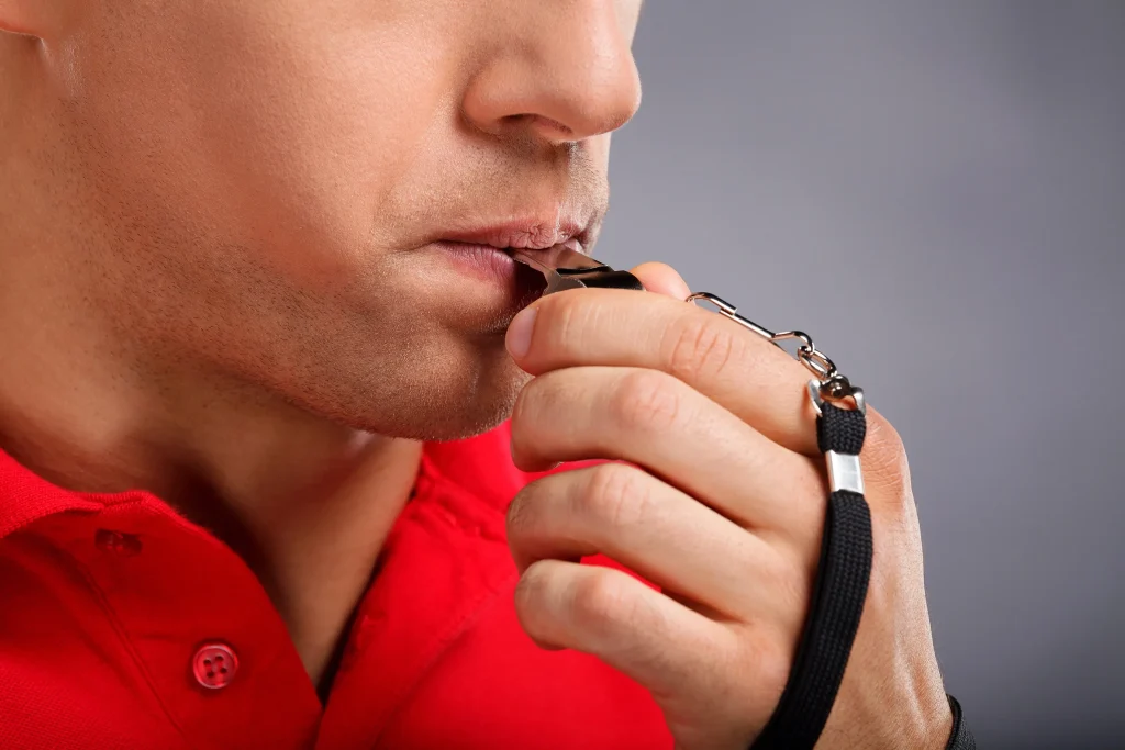Close up of man blowing whistle.