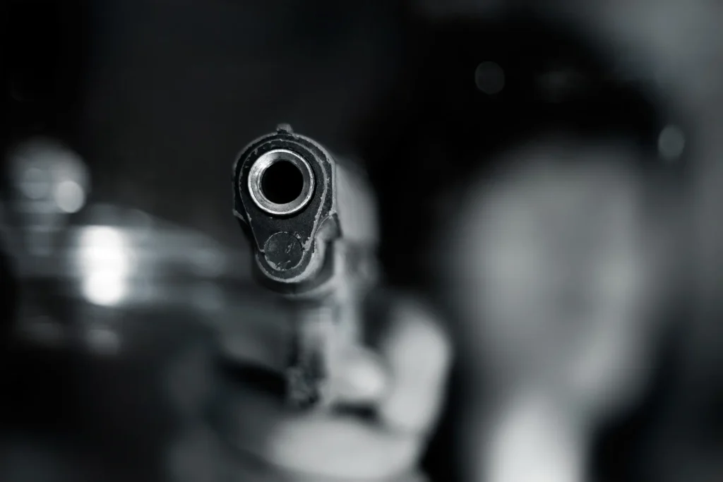 A gun being pointed at the camera in the dark.